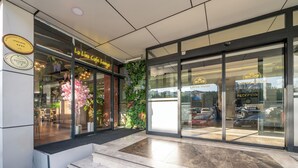 A hotel entrance with a reception area, a cafe, and a parking lot visible through the glass doors. - Litros Hotel & Spa (Istanbul)
