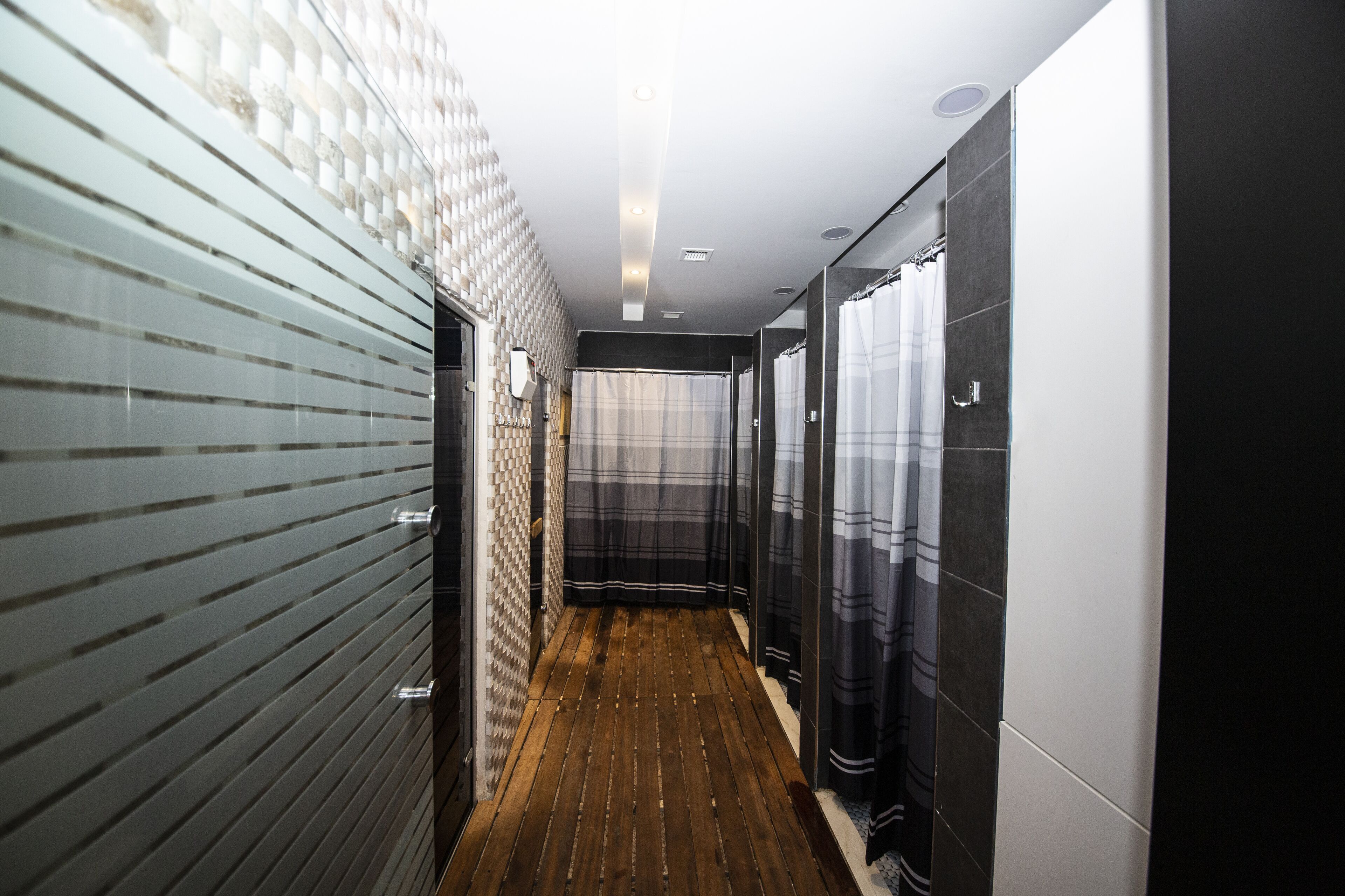 A narrow hallway with a wooden floor, tiled walls, and a modern design.