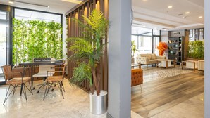 A modern hotel lobby with a reception desk, seating area, and a large window with a view of greenery. - Litros Hotel & Spa (Istanbul)