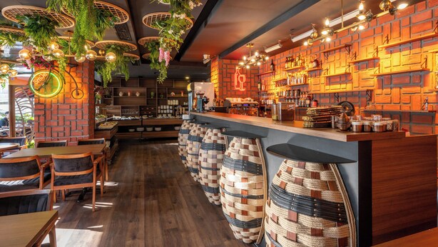 A restaurant with wooden tables and chairs, a brick wall, hanging plants, and a bar area with stools. - Litros Hotel & Spa (Istanbul)