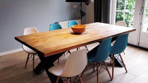 Ein Esstisch mit Holztischplatte, umgeben von vier Stühlen, wobei ein Stuhl blau ist.