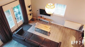 Un salon moderne avec un canapé, un banc en bois, une lampe sur pied et un téléviseur fixé au mur.
