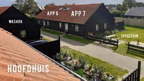 Un quartier résidentiel où les maisons sont identifiées par les panneaux « WASHOK », « APP 6 », « APP 7 » et « SPEELTUIN ».