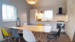 Une cuisine moderne équipée d’une cuisinière, d’un four et d’un évier. On y trouve également un coin repas avec une table et des chaises.