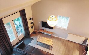 Una sala de estar moderna con un sofá, un banco de madera, una lámpara de pie y un televisor montado en la pared.