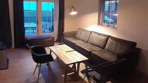 A living room with a leather sofa, a wooden coffee table, a black chair, and a small table.