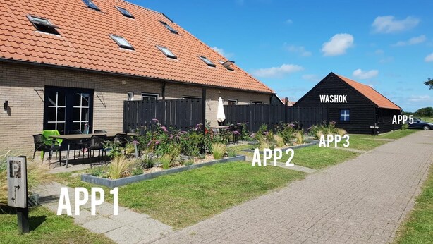 A building with a tiled roof, a wooden fence, and a paved walkway. - Newly renovated apartments on large grounds (Hollum)