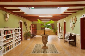 A hallway with a central potted plant, bookshelves, and a wooden ceiling. - Pet-Friendly 'Finca Rural Los Tanquillos' with Mountain View, Pool, Wi-Fi, A/C, Terrace & Garden (San Bartolomé de Tirajana)