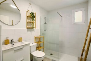 Een badkamer met toilet, wastafel, spiegel en douchecabine.