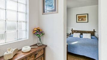 A bedroom with a bed, a nightstand, a window with blinds, and a framed picture on the wall.