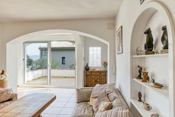 Un salon comprenant un canapé, un meuble en bois et une étagère ornée d’objets décoratifs.