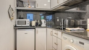 A compact kitchen with white cabinets, a microwave, a coffee maker, and a dishwasher. - Casa Familia Pestana 1, a Home in Madeira (Seixal)