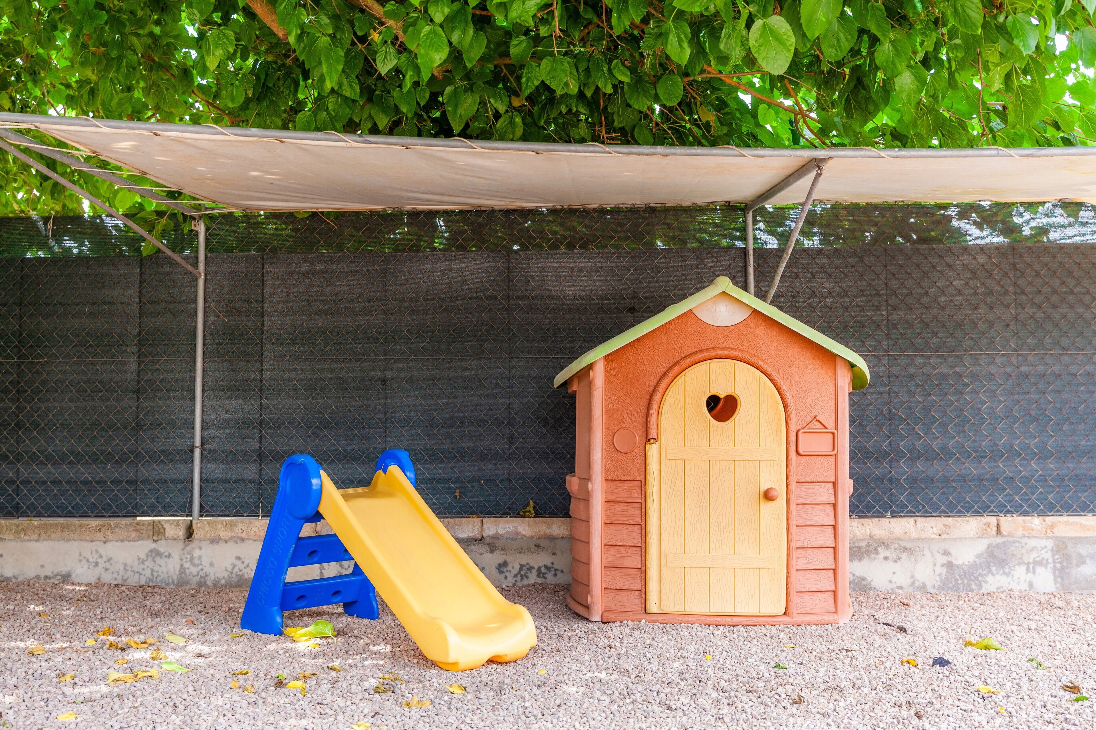 Een speelruimte voor kinderen met een glijbaan en een klein huisje.