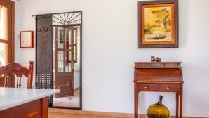 Una habitació amb escriptori de fusta, mirall, quadre amb marc i porta amb cortina.