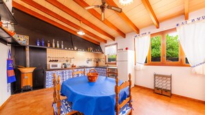 Una cuina amb bigues de fusta, un taulell blau i una finestra amb cortines.