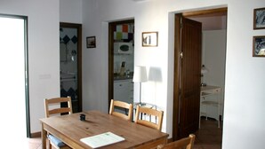 A dining area with a wooden table and four chairs, a lamp, and a door leading to another room.