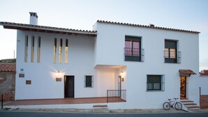 A two-story white building with a tiled roof, a bicycle parked outside, and a wheelchair-accessible ramp.