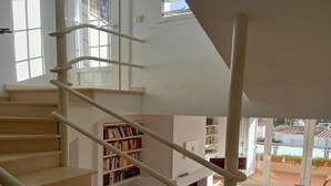 Un escalier menant à un balcon agrémenté d’étagères à livres et offrant une vue sur une cour intérieure.