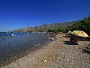 A beach with clear water, people swimming, and boats.