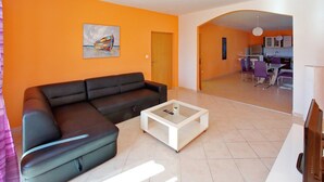 Una sala de estar con un sofá negro, una mesa de centro de vidrio y un cuadro en la pared.
