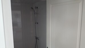 En dusch med ett justerbart duschmunstycke och en väggmonterad blandare.