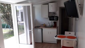 Ett kompakt kök med diskmaskin, mikrovågsugn och ett litet bord med orange bordsunderlägg.