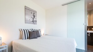 A modern bedroom with a large bed, a bedside table, a wall-mounted picture, and a sliding door to a bathroom. - Apartment in Zeeland with Private Jetty (Kamperland)