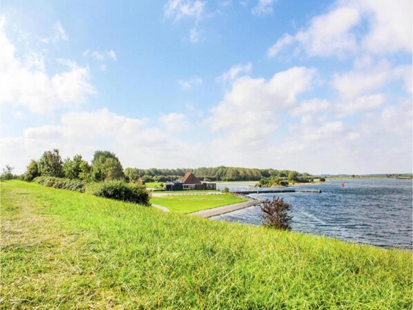A lakeside property with a grassy area, a small building, and a dock extending into the water.