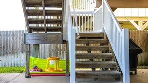 A wooden staircase with a white railing leading to a deck area.