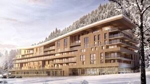 Ein mehrstöckiges Hotel mit Balkonen, einer Steinfassade und einer verschneiten Landschaft.