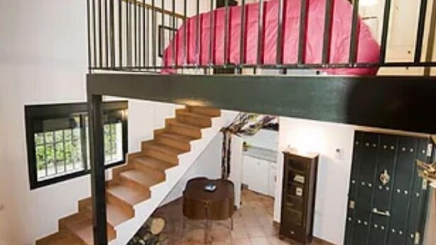 Un loft spacieux avec un escalier en bois, un canapé, une petite table et une grande fenêtre.