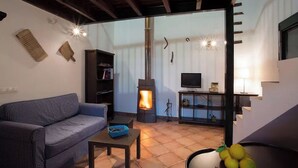 Un salon confortable avec un canapé, une petite table, une bibliothèque, une cheminée et un téléviseur.