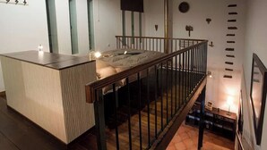 Un intérieur moderne avec un plancher en bois, un petit îlot-comptoir et un escalier menant à un niveau supérieur.