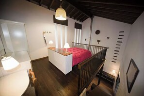 Une chambre avec un lit superposé, un bureau recouvert d’une housse de lit rose et un luminaire suspendu.