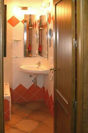Une salle de bain avec un lavabo, un miroir et des murs recouverts de carreaux rouges.