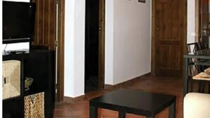 Un salon avec un téléviseur, un canapé, une table et une chaise.