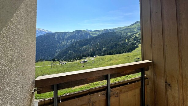 Un balcón de madera con vistas a un paisaje montañoso.