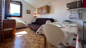 Un espacio habitable compacto con sofá, mesa de comedor y microondas.