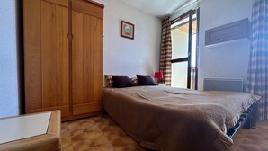 Un dormitorio con una cama grande, un armario, un escritorio y una ventana con cortinas.