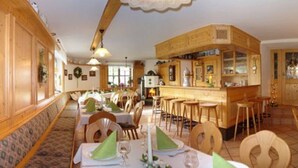 A restaurant with wooden interiors, multiple dining tables, and a bar area. - Landhotel Zur Pferdetränke (Schleid)