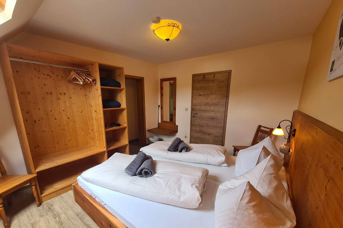 A bedroom with two beds, wooden furniture, a wardrobe, and a mirror.