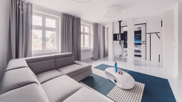 Un salon moderne avec un canapé gris, de grandes fenêtres et un design minimaliste.