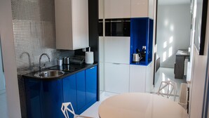Une cuisine moderne avec des meubles bleus, un évier et une table à manger blanche.