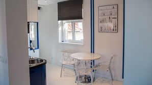 Une cuisine moderne avec un plan de travail blanc, un évier et une fenêtre donnant sur les bâtiments environnants.
