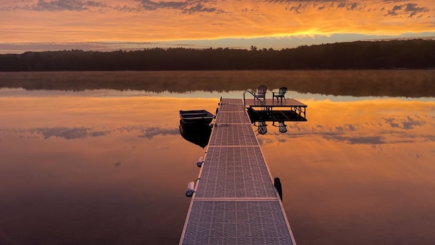 A pier extending into calm waters with a sunset in the background.