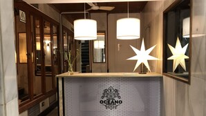 Un comptoir d’accueil d’hôtel au design moderne, orné d’un logo et surmonté d’un luminaire en forme d’étoile.