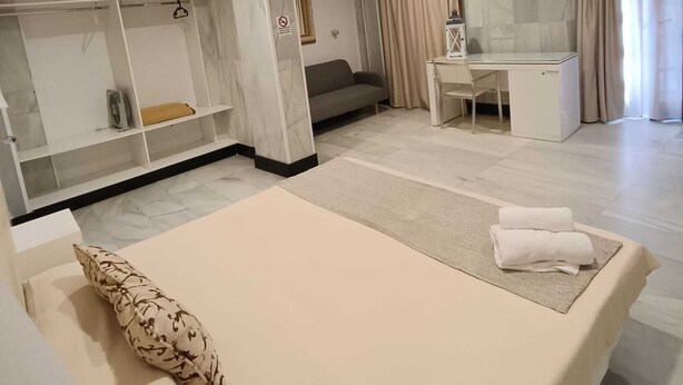 Une chambre d’hôtel moderne équipée d’un lit, d’un bureau, d’un canapé et d’une armoire.