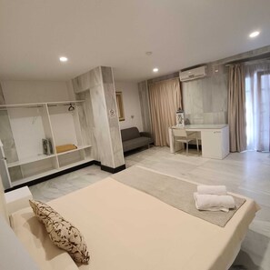 Een moderne hotelkamer met een bed, een bureau, een bank en een kledingkast.