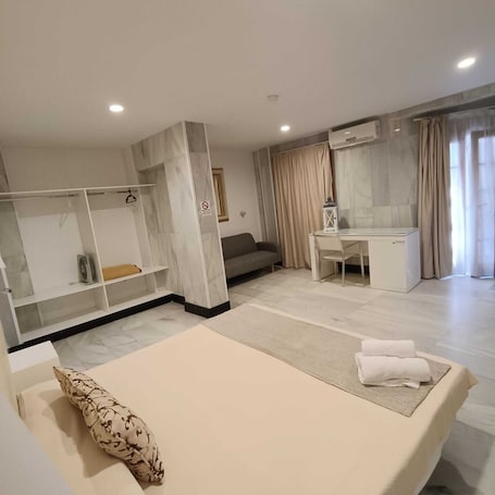 A hotel room with a bed, a desk, a sofa, and a wardrobe.