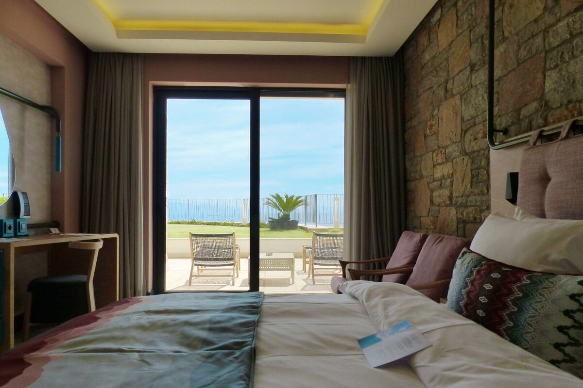 A hotel room with a bed, a desk, and a view of the outdoors.